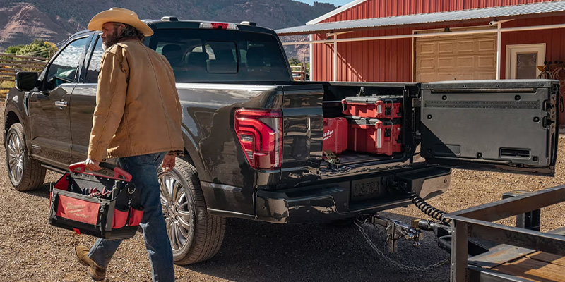a man grabbing tools out of the back of a 2025 Ford F-150